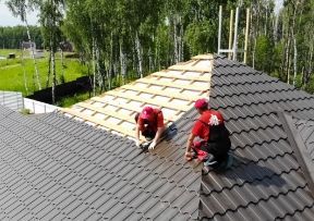 Roofers installing metal roofing on a house.
