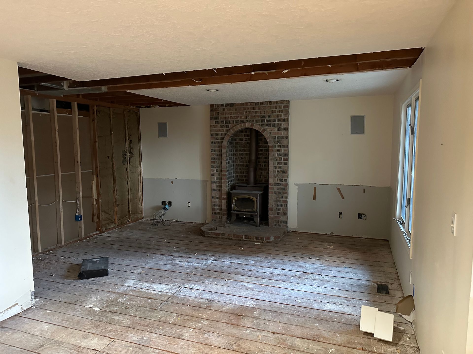 An empty room with a brick fireplace in the middle of it.