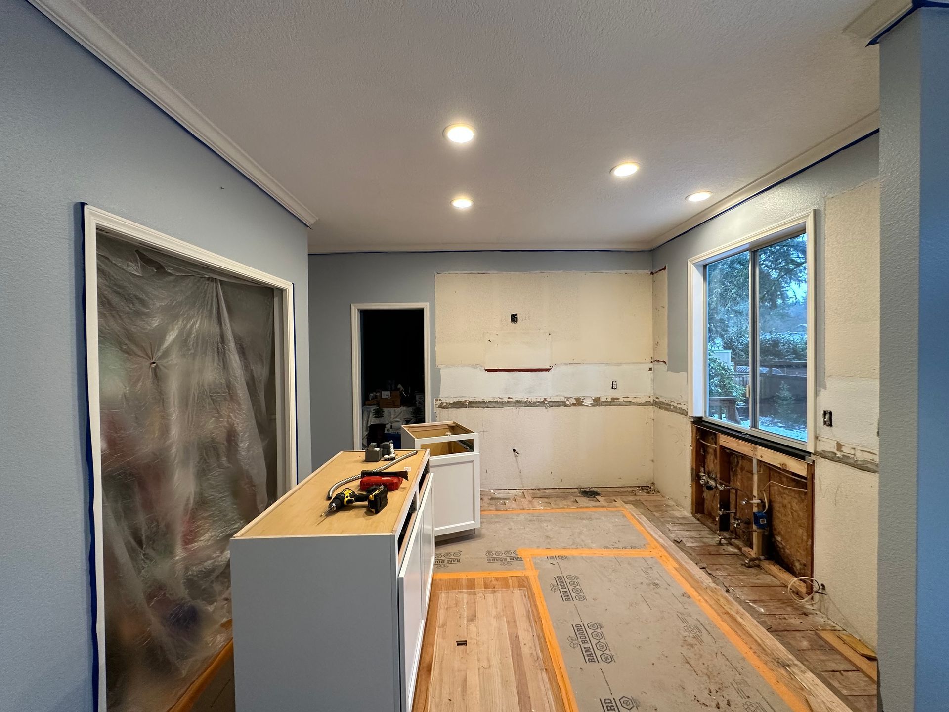 A kitchen under construction with a lot of cabinets and wooden floors.