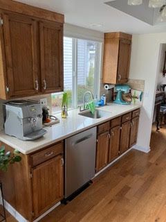 A kitchen with wooden cabinets , stainless steel appliances , a sink , and a window.