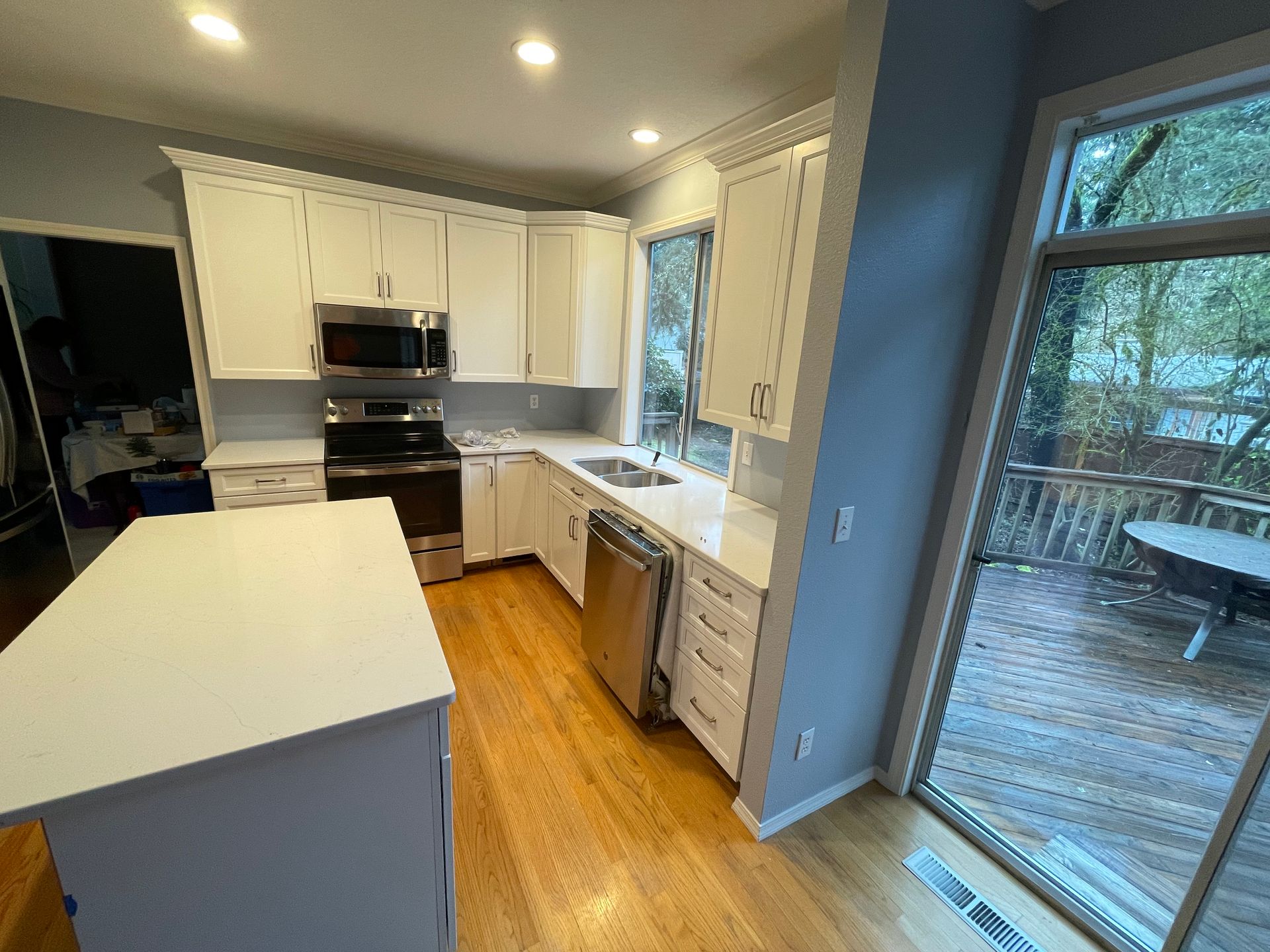 A kitchen with white cabinets , stainless steel appliances , and a large island.