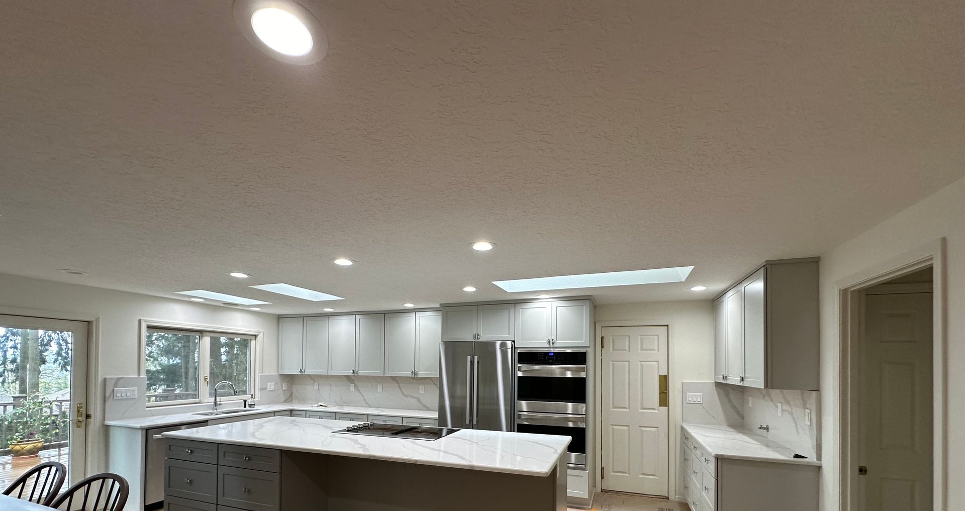 A kitchen with white cabinets , stainless steel appliances , and a large island.