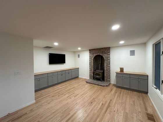 A living room with hardwood floors , a fireplace and a flat screen tv.