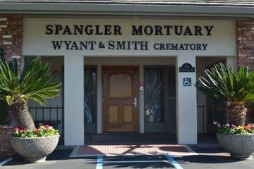A cream-colored building with a dark wooden arched door and a sign reading