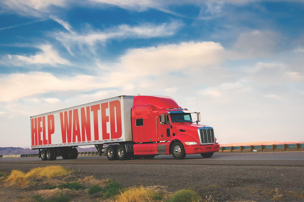 A red semi truck with a help wanted sign on the side of it.