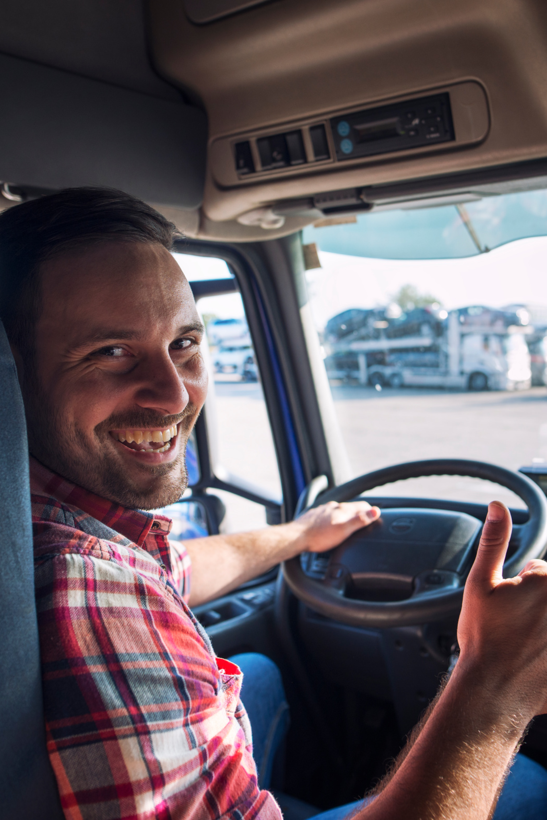 A man is sitting in the driver 's seat of a truck giving a thumbs up.