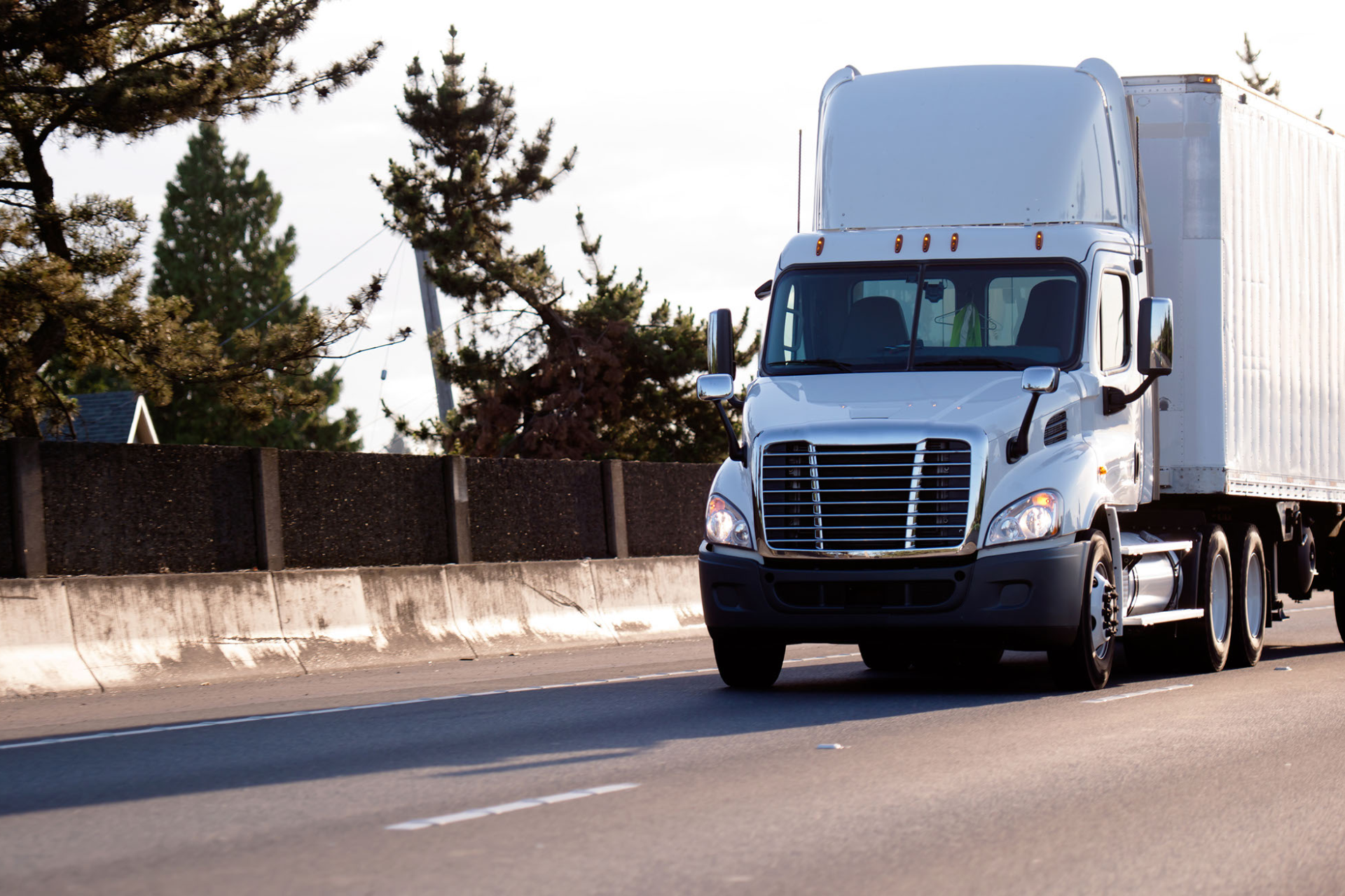 A white semi truck is driving down a highway.