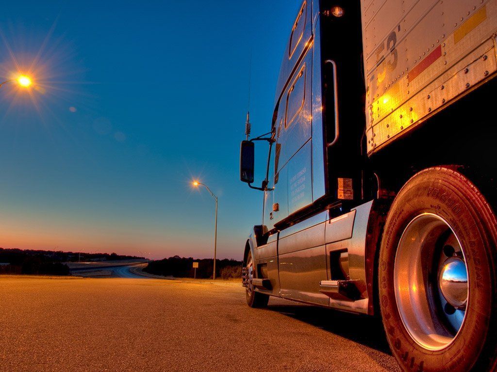 A semi truck is parked on the side of the road at night