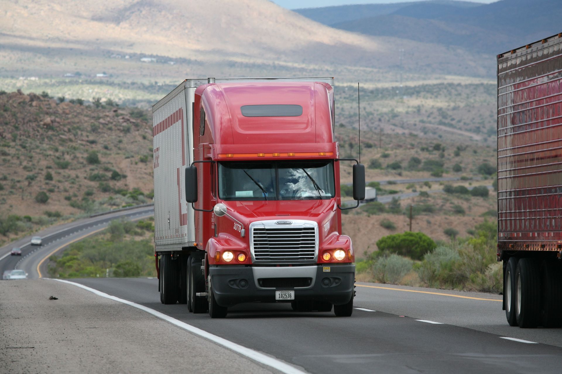 A semi truck is driving down a highway at night.