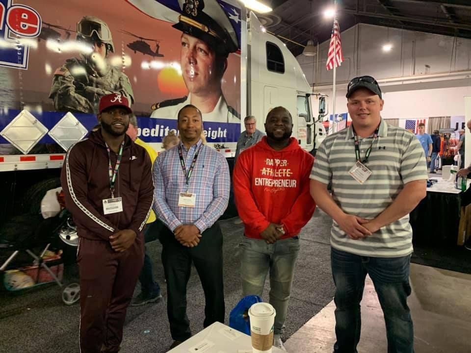 A group of men are standing next to each other in front of a truck.