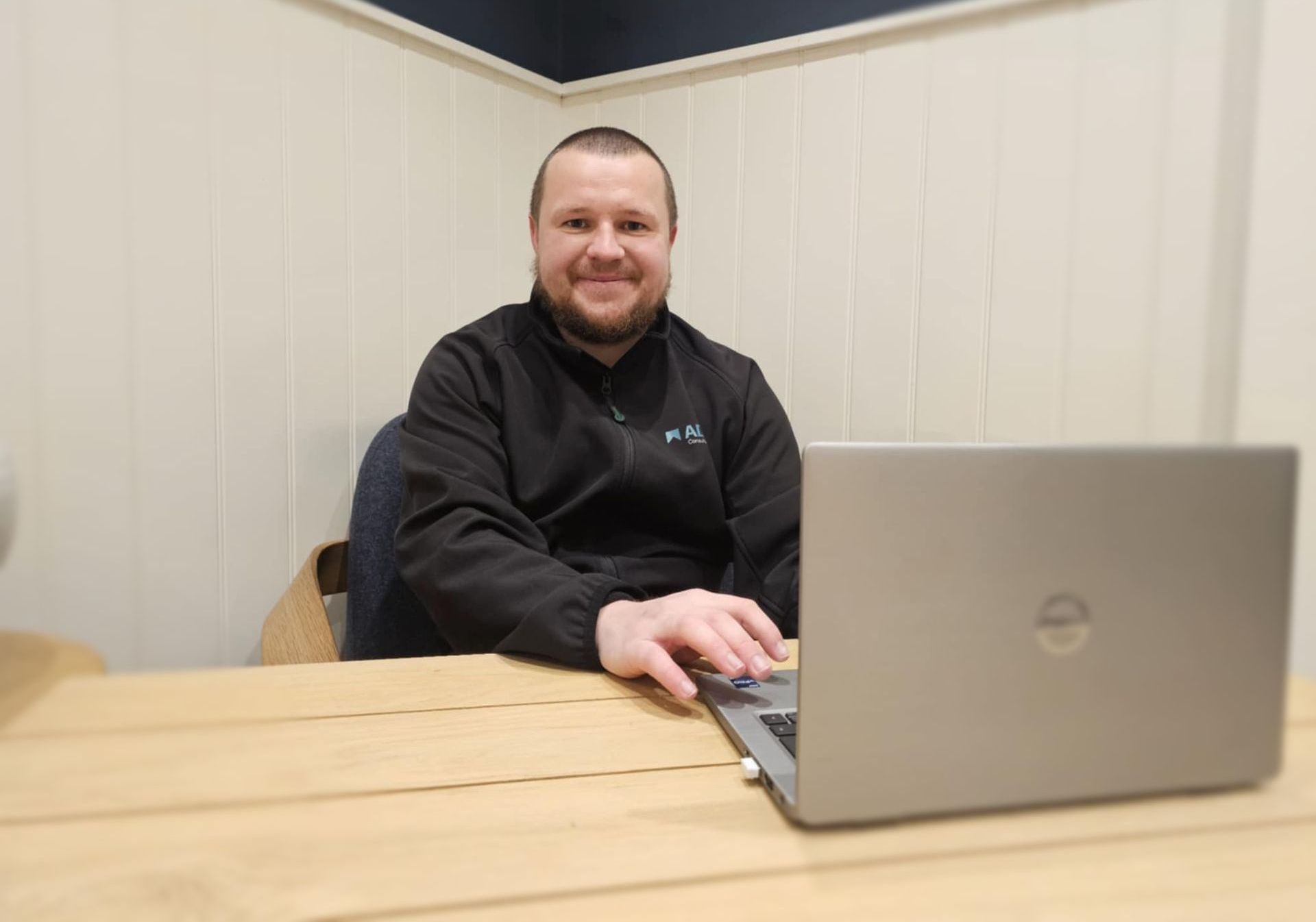 A man wearing glasses is sitting at a table using a laptop computer.