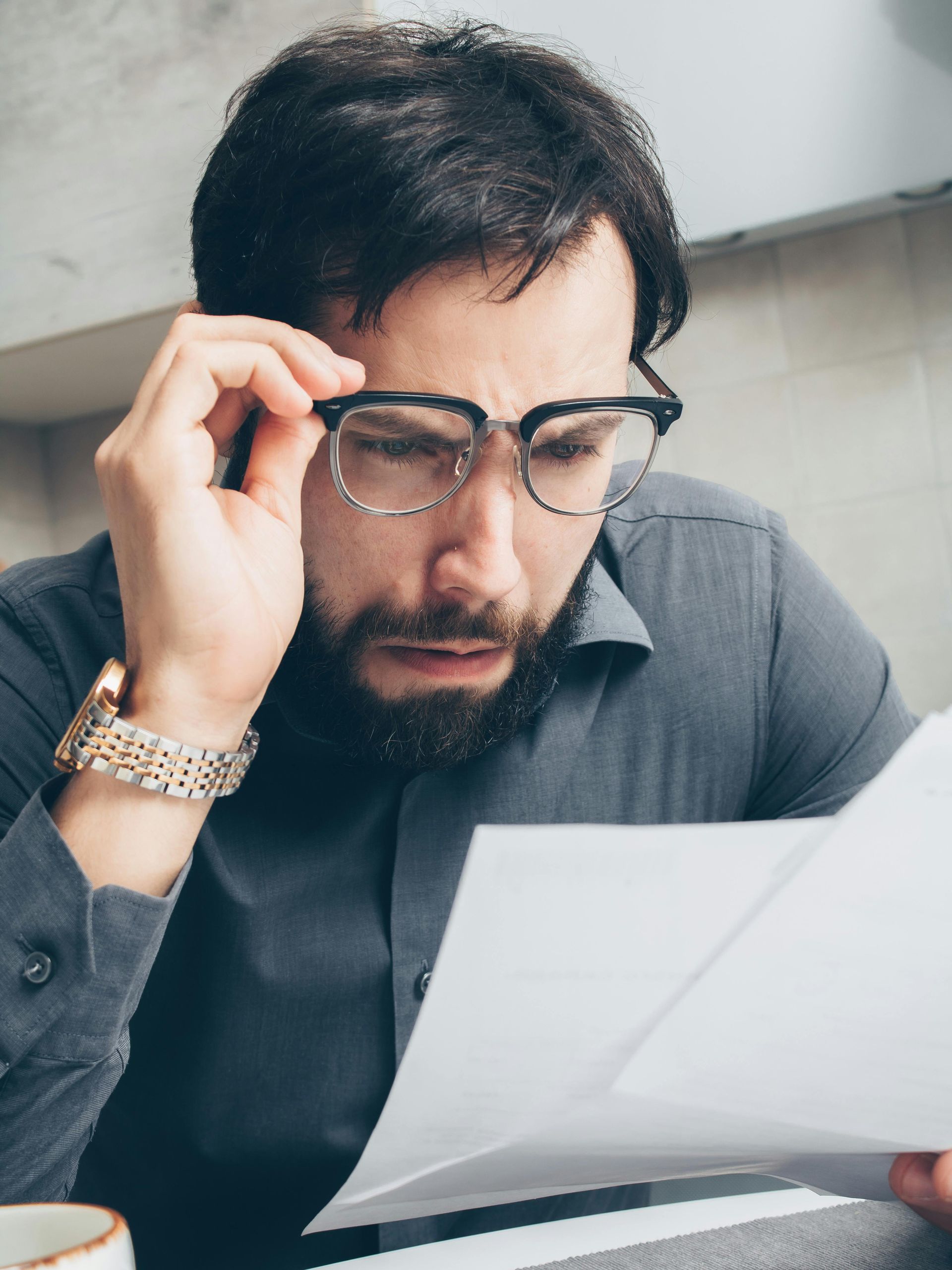 A man wearing glasses is reading a piece of paper