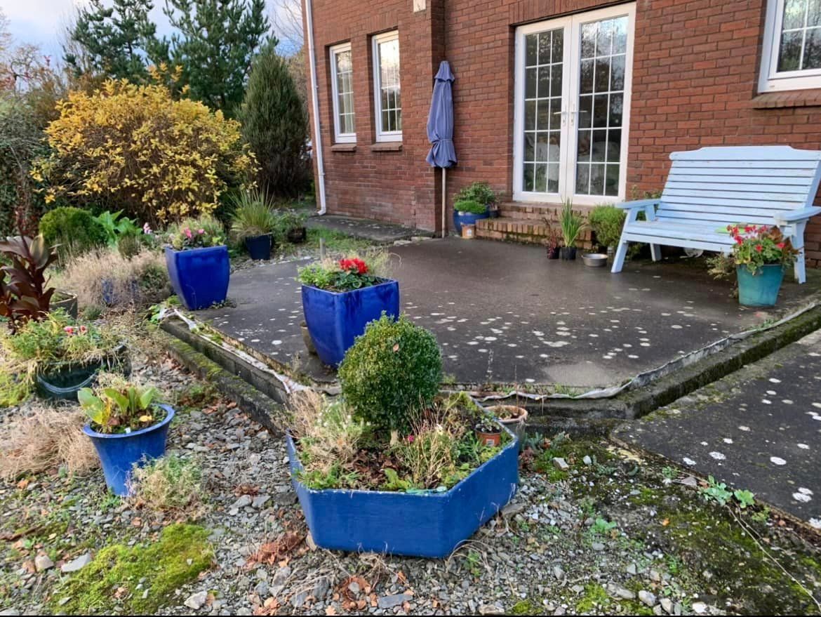 A patio with blue potted plants and a bench in front of a brick building.