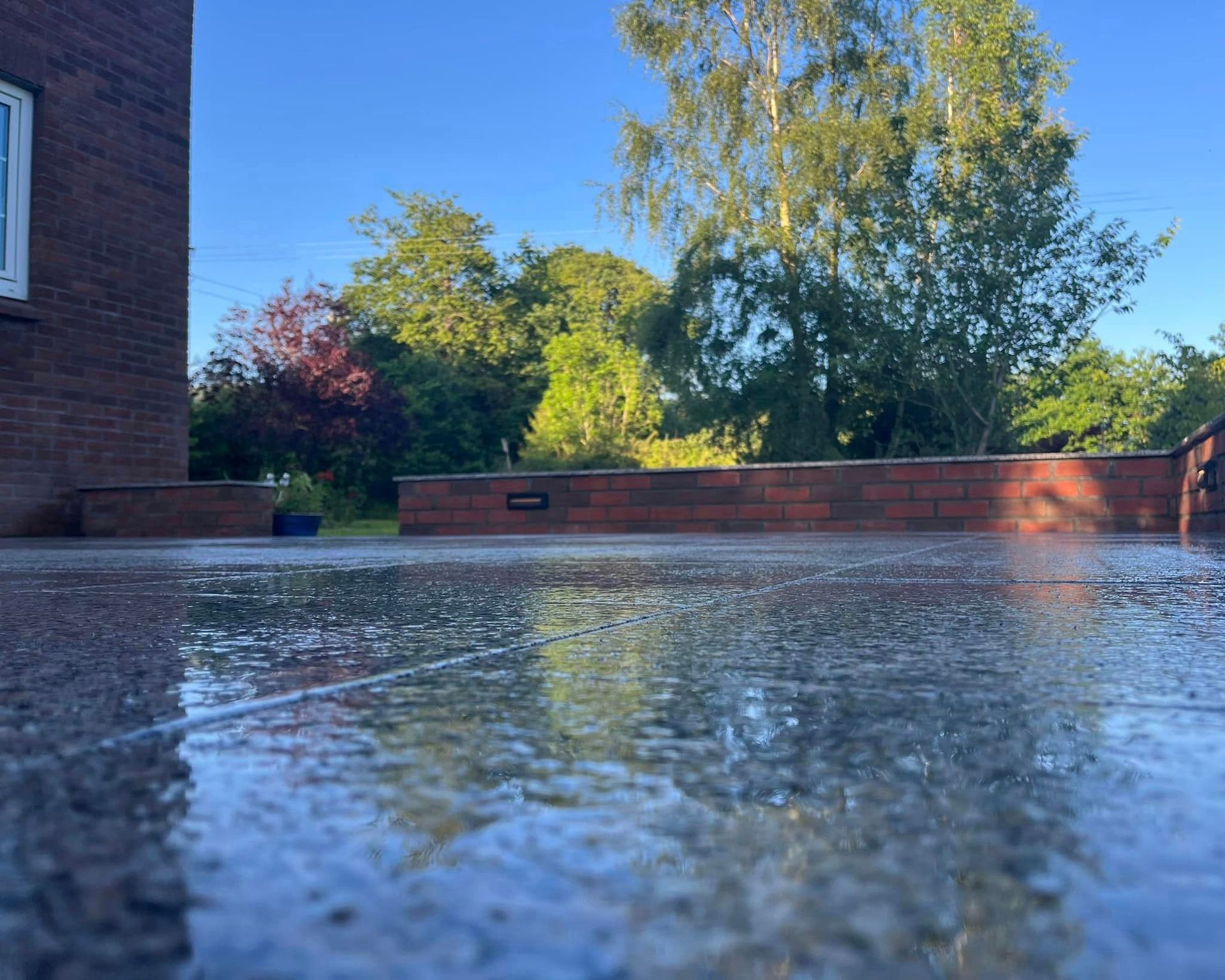 A puddle of water is on the ground in front of a brick building.