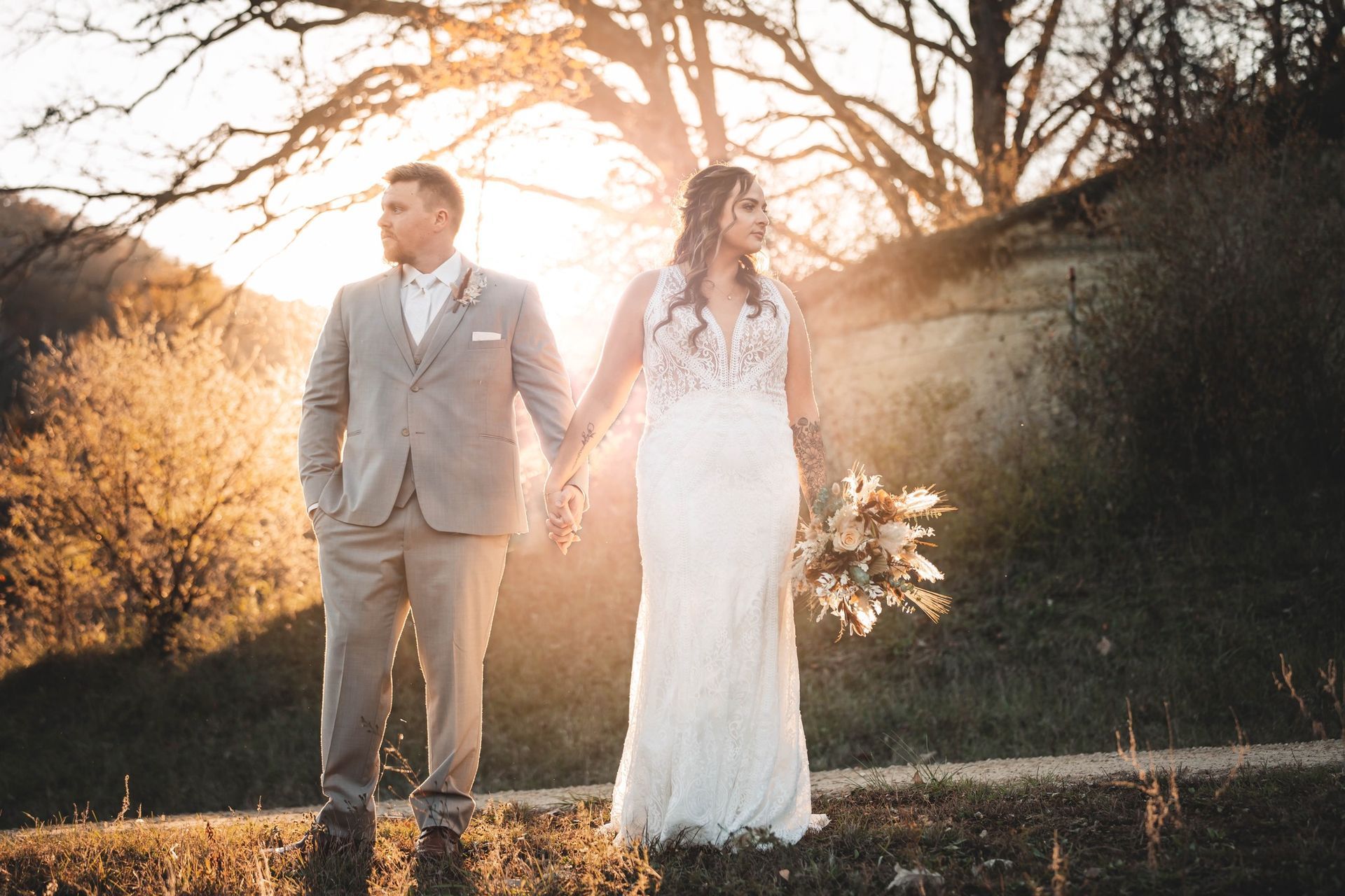 A bride and groom are holding hands in a field at sunset. A bride and groom are holding hands in a field at sunset.