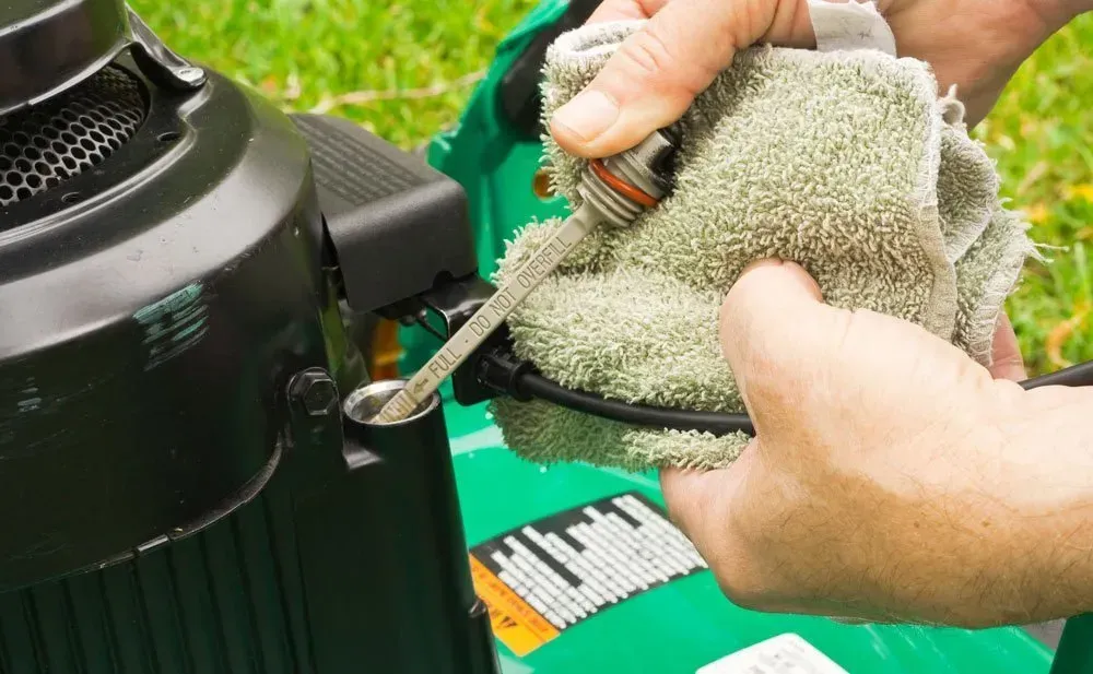 A Person is Cleaning a Lawn Mower With a Towel and Oil — Jacksons Mower Centre in Mackay, QLD