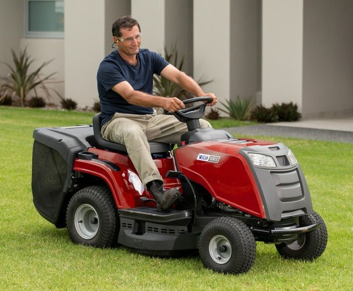 A Man is Riding a Lawn Mower on a Lush Green Lawn — Jacksons Mower Centre in Mackay, QLD