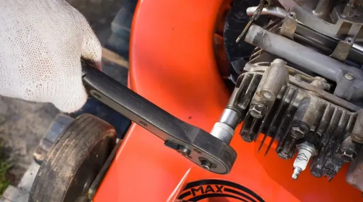 A Person is Working on a Lawn Mower With a Wrench — Jacksons Mower Centre in Mackay, QLD