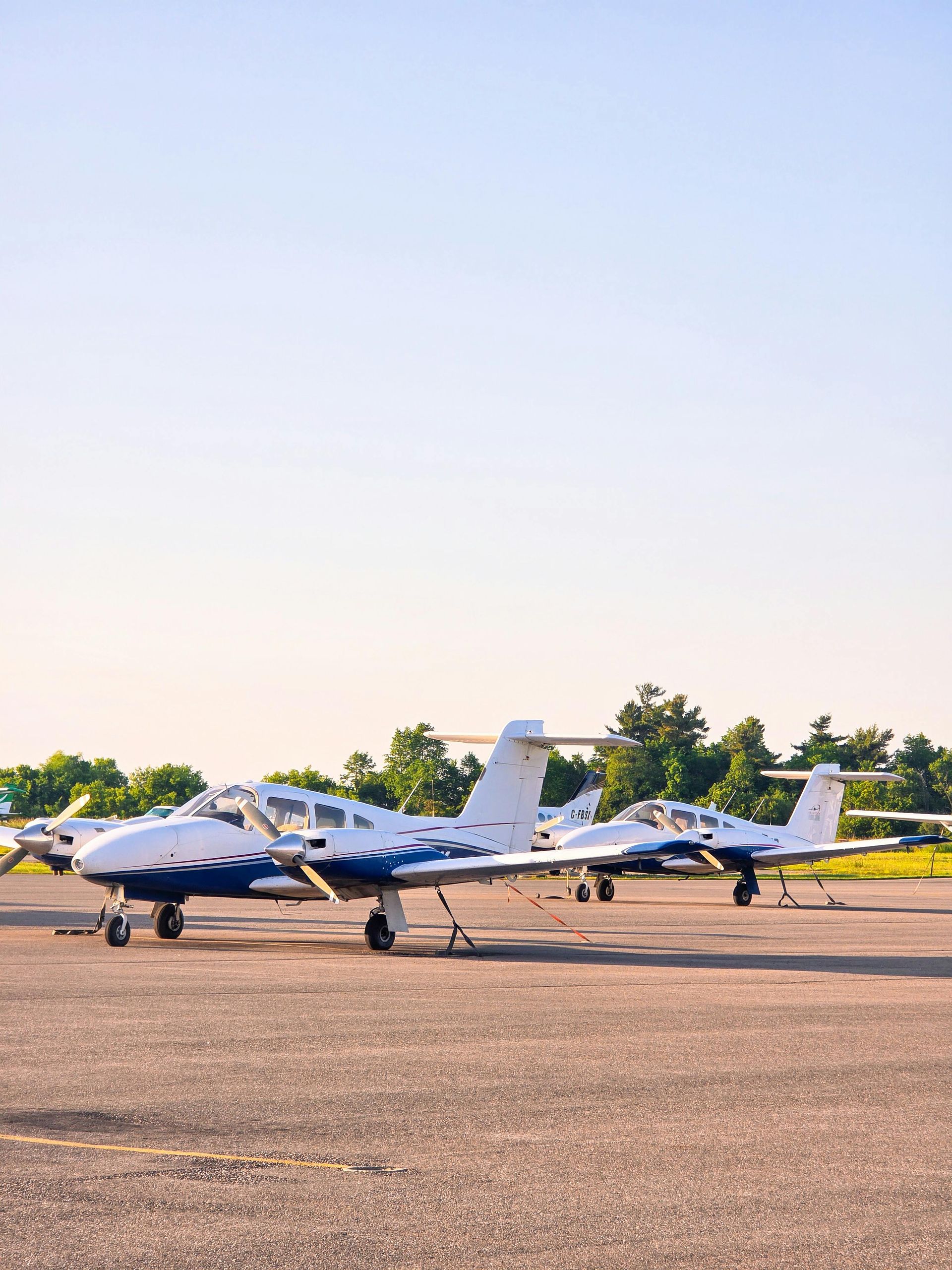 Small white airplanes parked on a runway at an airfield at sunset