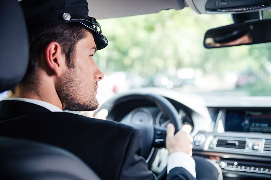 A man in a suit and hat is driving a car.