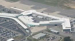An aerial view of an airport with a lot of cars parked in front of it.