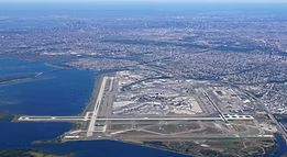 An aerial view of an airport surrounded by water and a city.