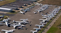 An aerial view of a row of planes parked on a runway.