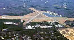 An aerial view of a small airport surrounded by trees and buildings.