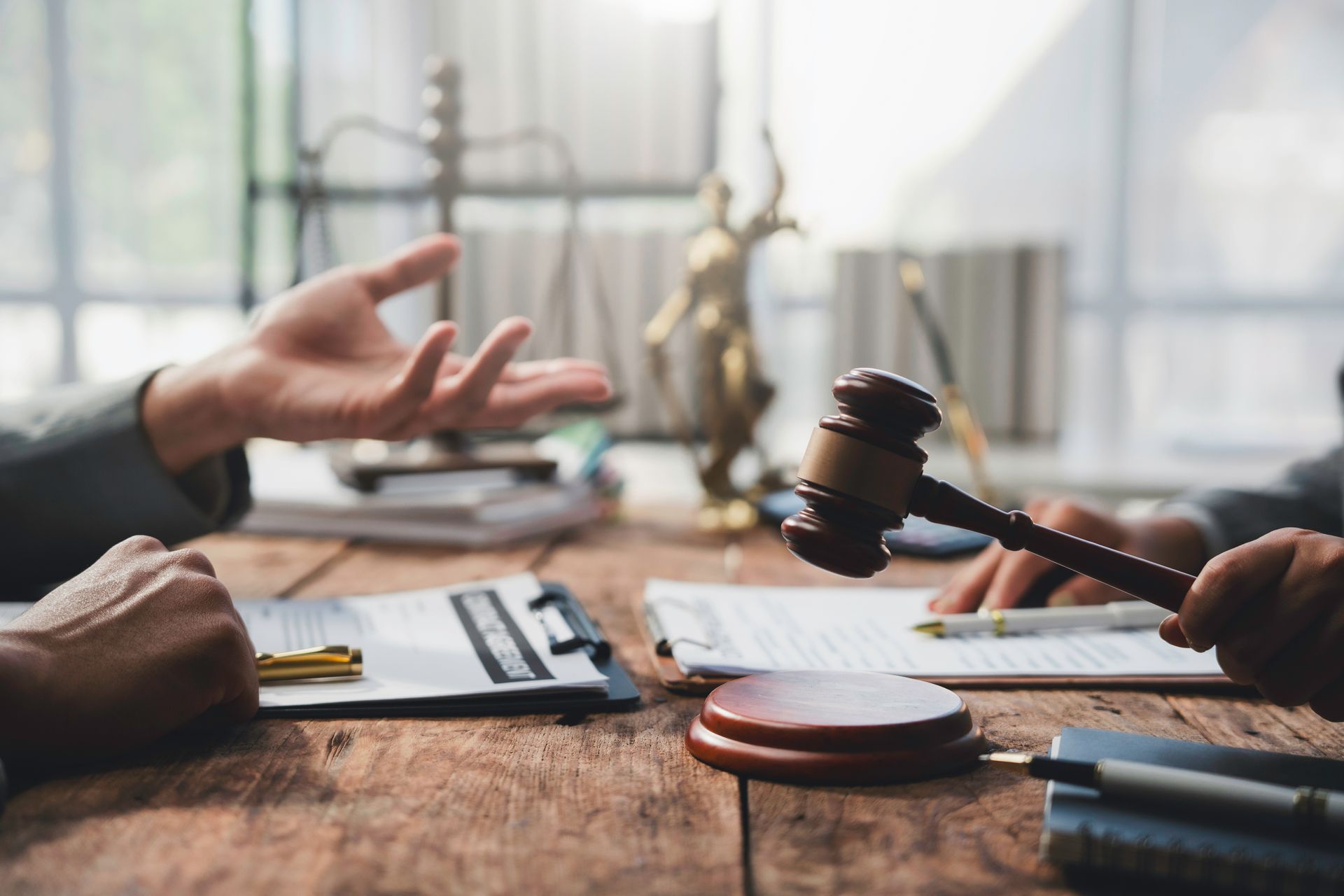 Judge’s gavel on desk during a legal consultation with documents and scales.
