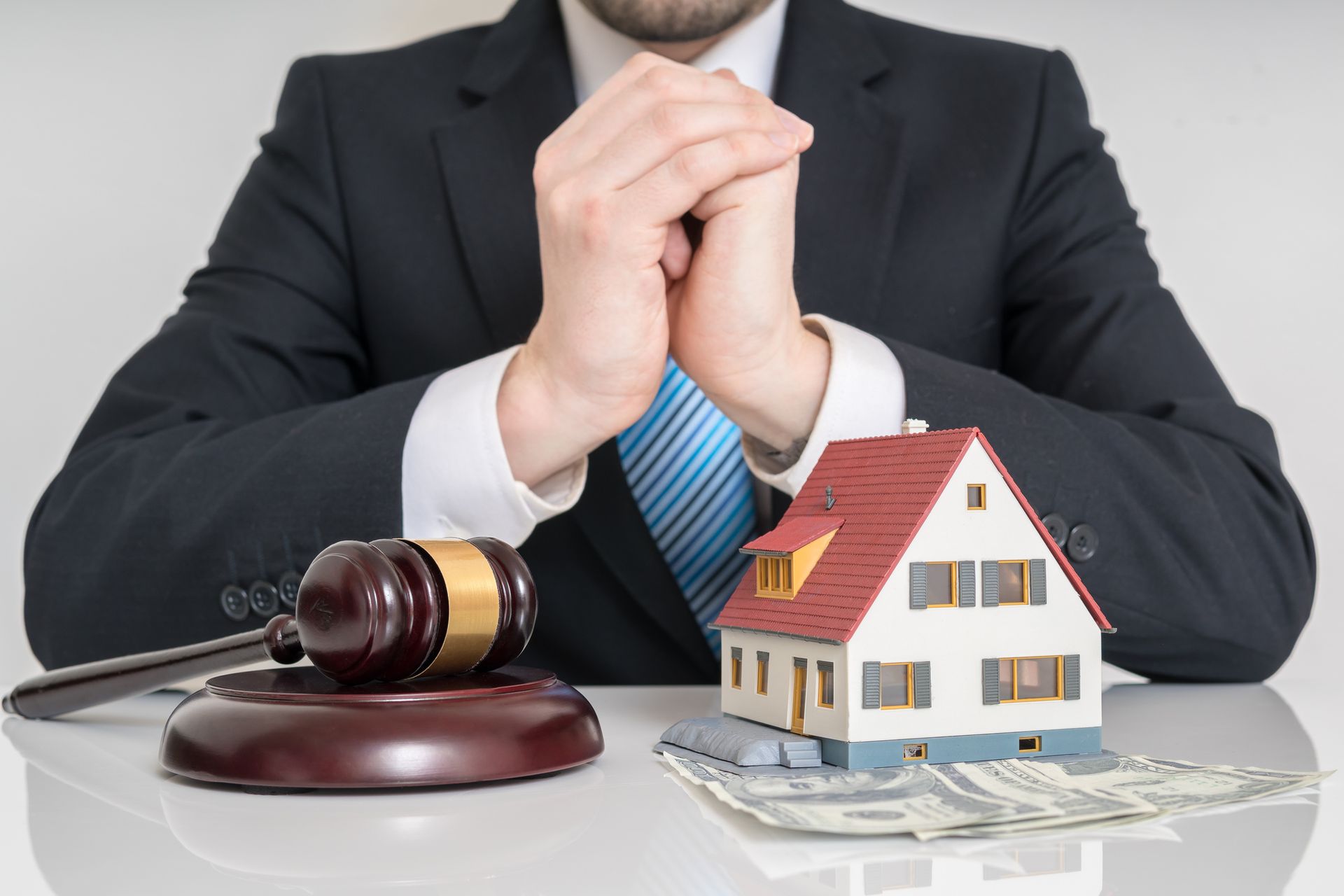 Small house and gavel on a table in front of lawyer, representing bankruptcy attorney services.