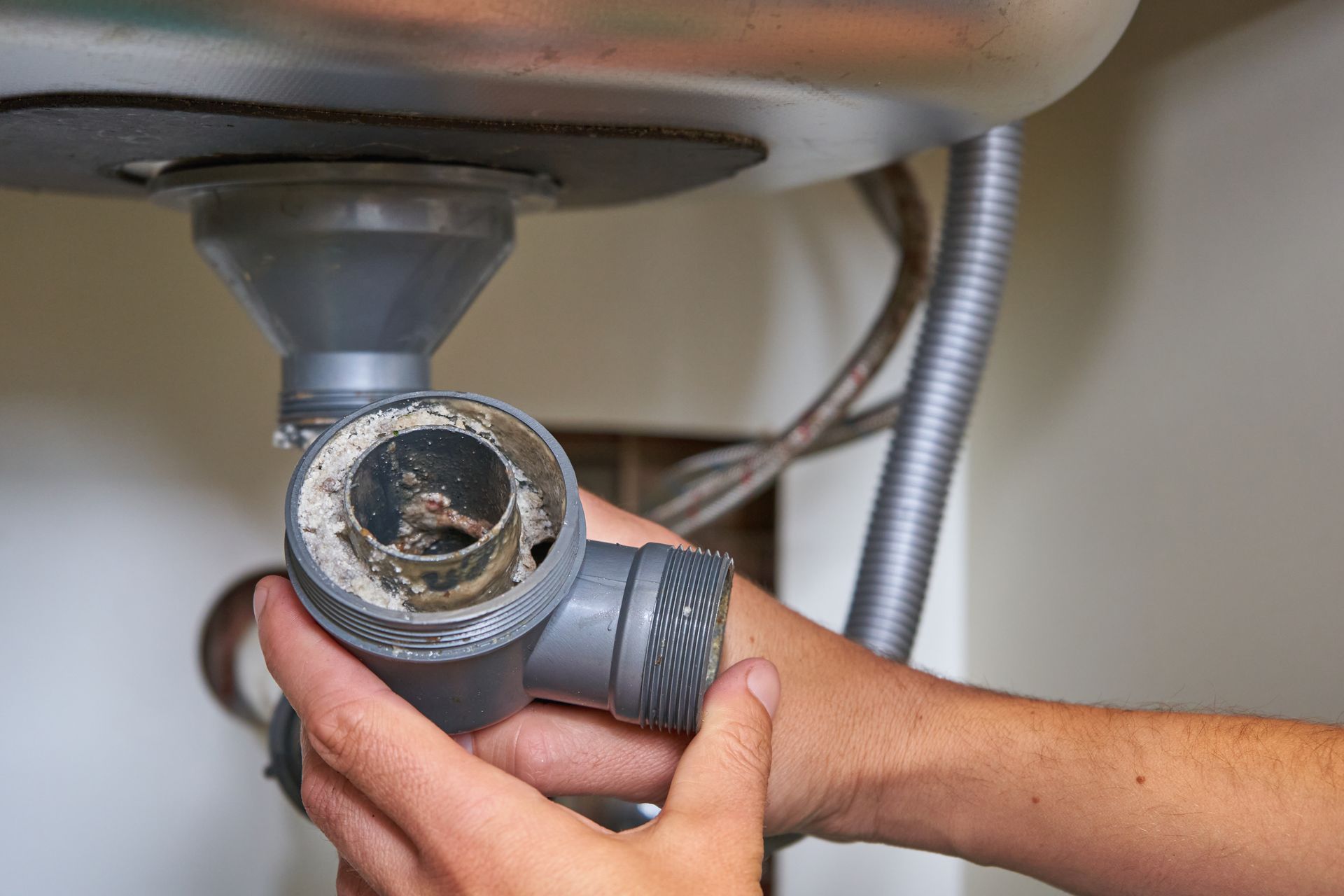 Plumber performing clogged drains cleaning on a blocked sink trap. Plumber performing clogged drains cleaning on a blocked sink trap.