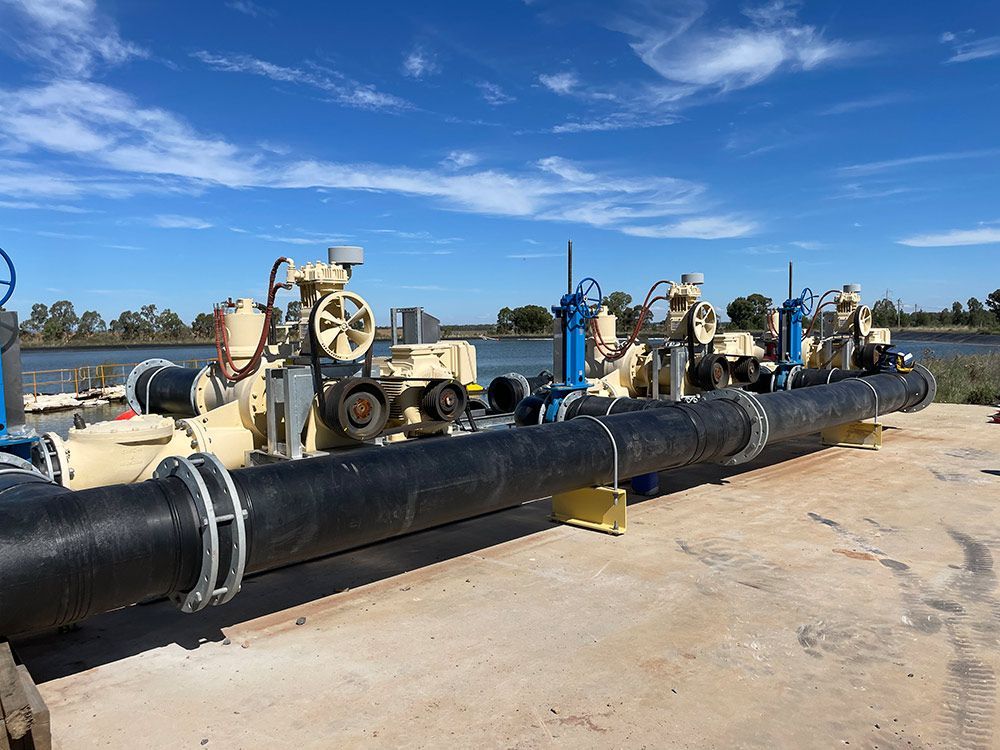 A Row of Pipes Sitting on Top of A Concrete Surface Next to A Body of Water — BJB Plumbing & Gasfitting in Cobar, NSW