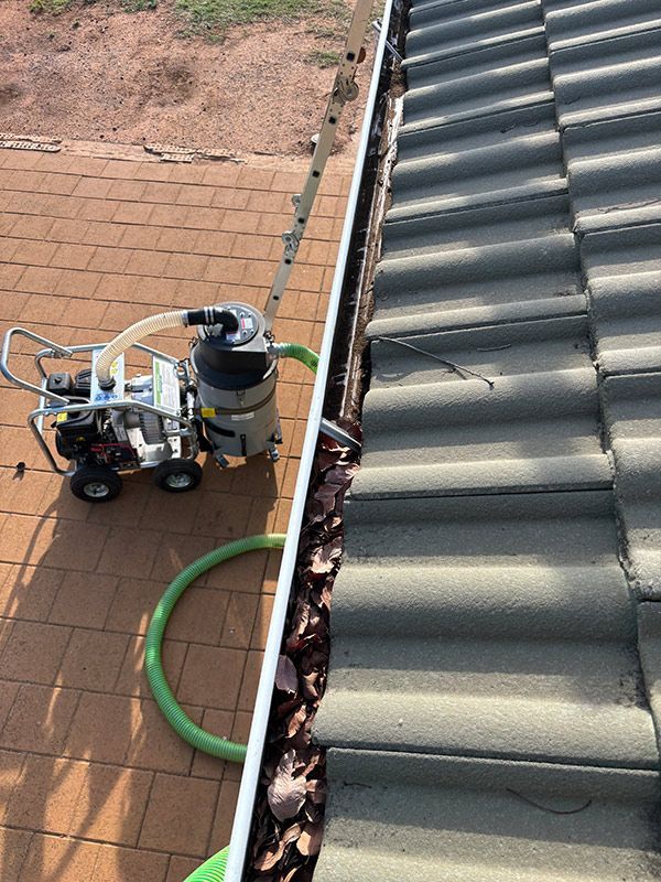 A Vacuum Cleaner Is Being Used To Clean A Gutter On A Roof — BJB Plumbing & Gasfitting in Dubbo, NSW