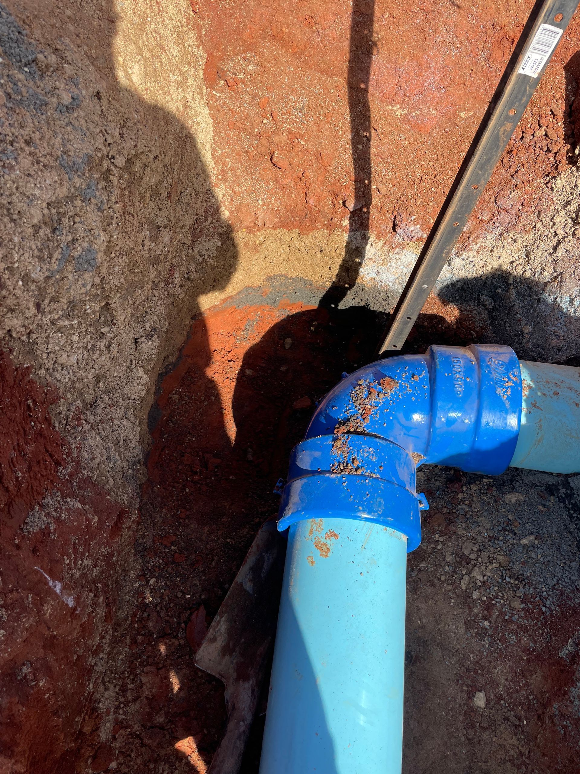 A Blue Pipe Is Sitting in The Dirt Next to A Rock — BJB Plumbing & Gasfitting in Dubbo, NSW