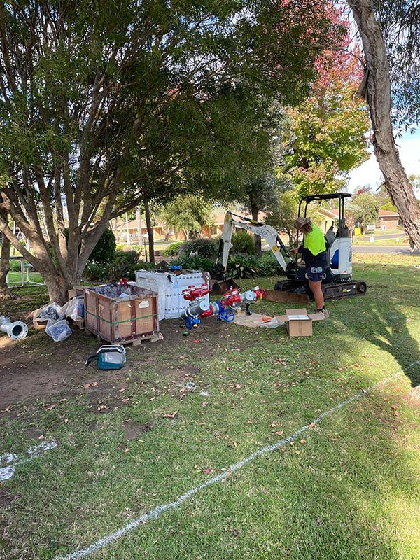 A Man Is Working on A Golf Cart in A Park — BJB Plumbing & Gasfitting in Coonabarabran, NSW