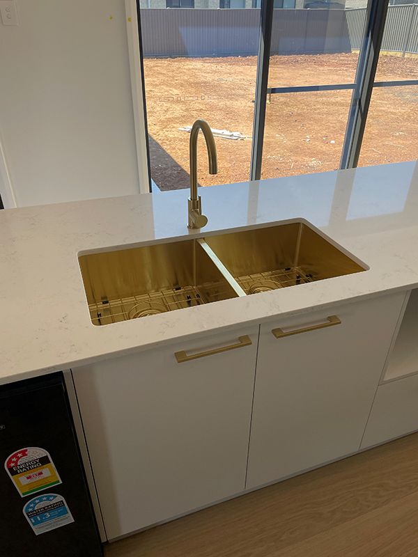 A Man Is Fixing a Faucet in A Bathroom — BJB Plumbing & Gasfitting in Parkes, NSW