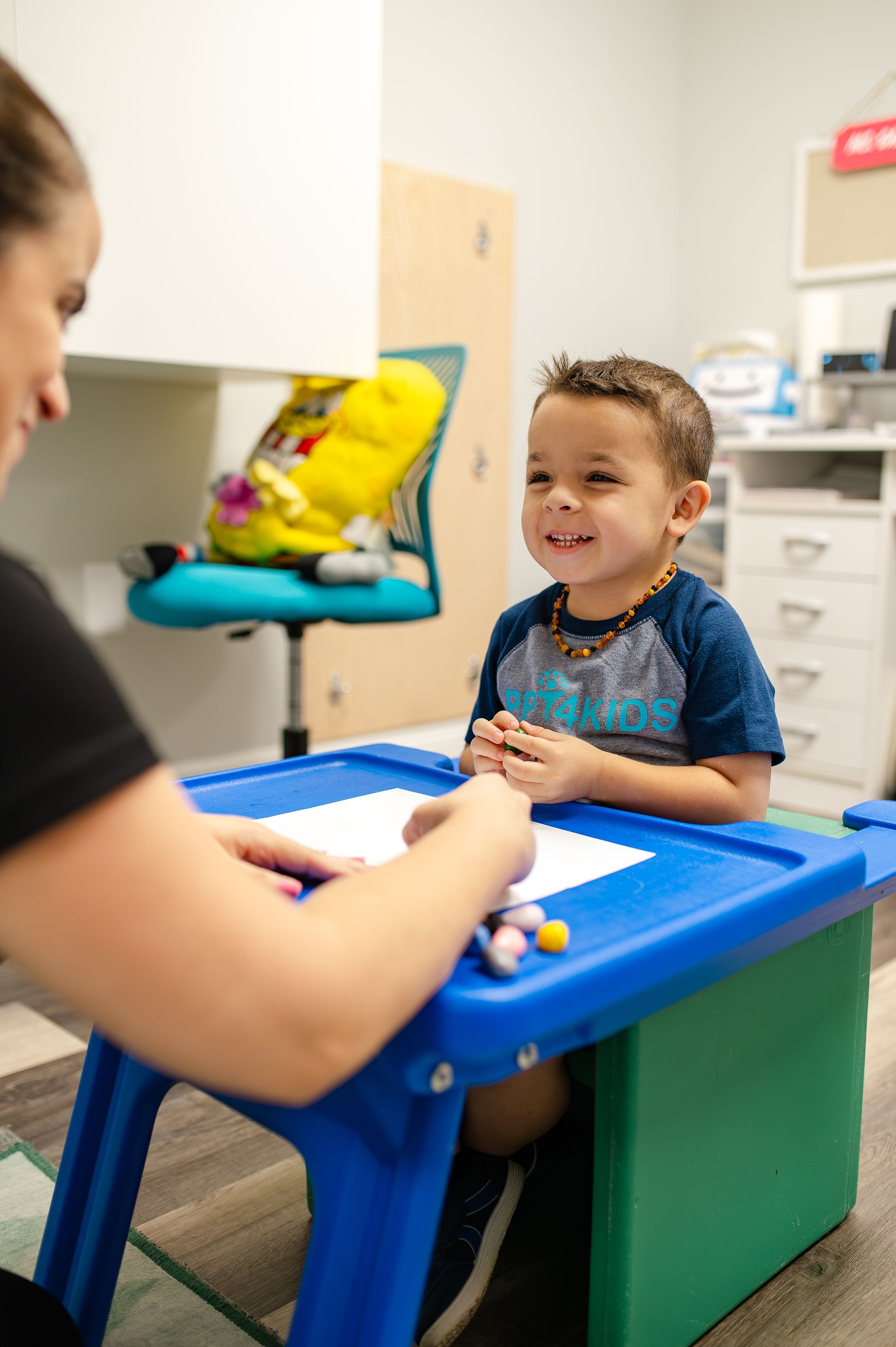 Adult and child playing with a soccer ball in a room with a bench and toys.
