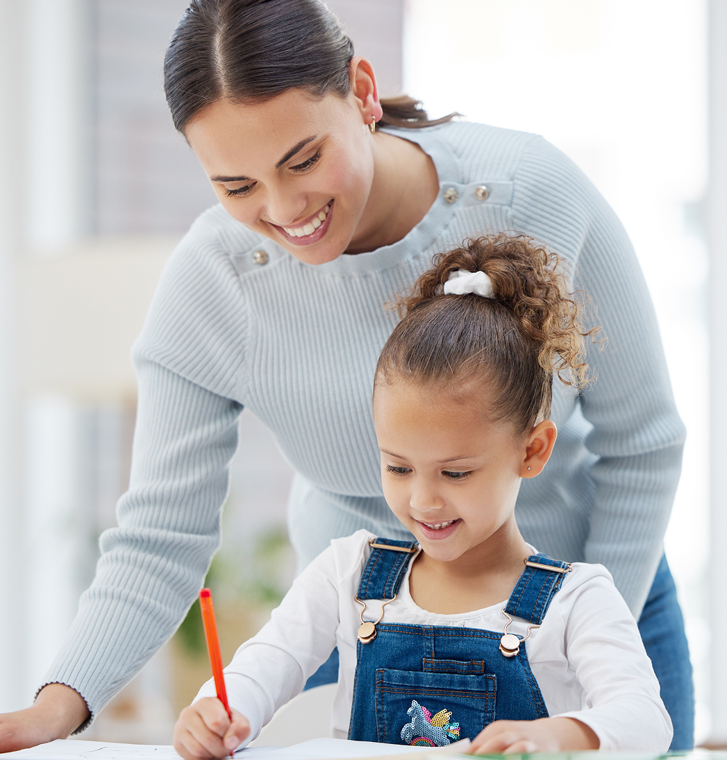 Adult and child smiling while drawing together at a table with a red pencil