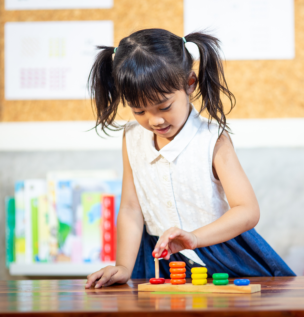 Young child stacking colorful blocks on a table in a classroom setting