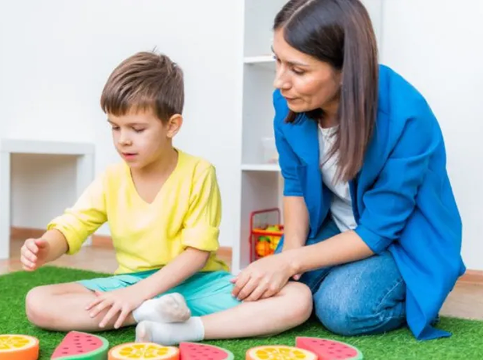 Adult and child playing with colorful toy rings on a green rug indoors