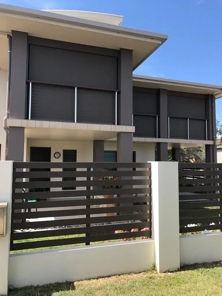 A Large House With a Fence in Front of It — Dennys Upholstery & Outdoor Blinds In Ballina, NSW