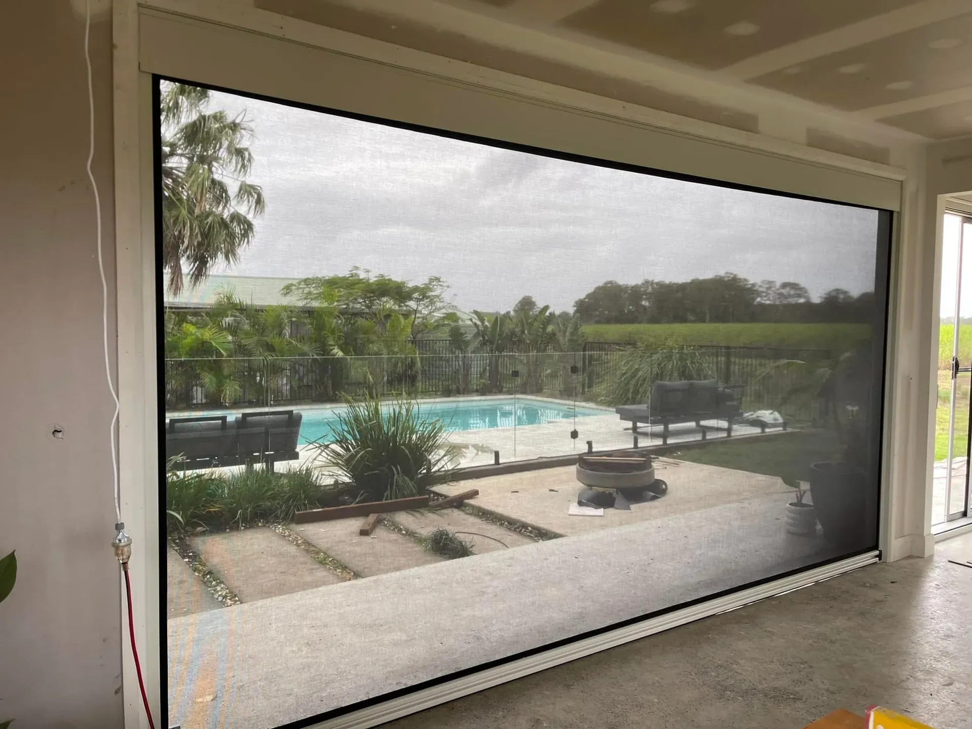 A Large Screen Door With a View of a Swimming Pool — Dennys Upholstery & Outdoor Blinds In Ballina, NSW
