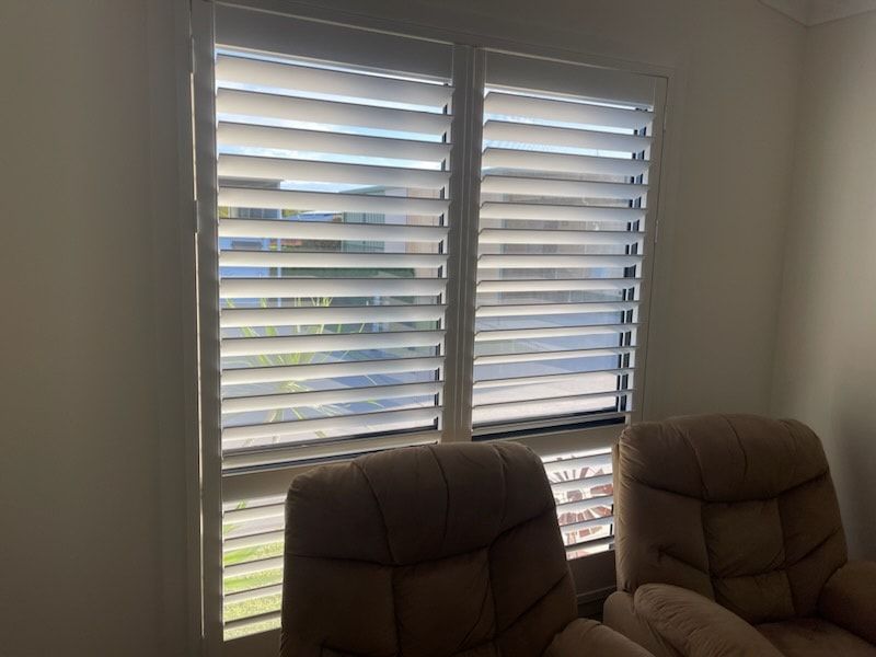 A Living Room With Two Chairs and Shutters on the Windows — Dennys Upholstery & Outdoor Blinds In Lismore, NSW