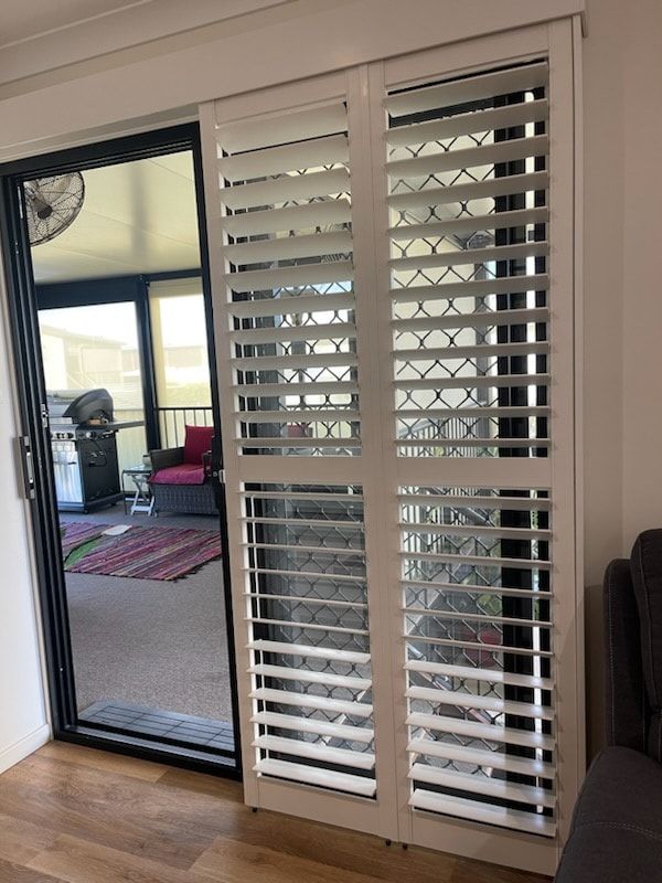 A Living Room With a Sliding Glass Door and White Shutters on It — Dennys Upholstery & Outdoor Blinds In Casino, NSW