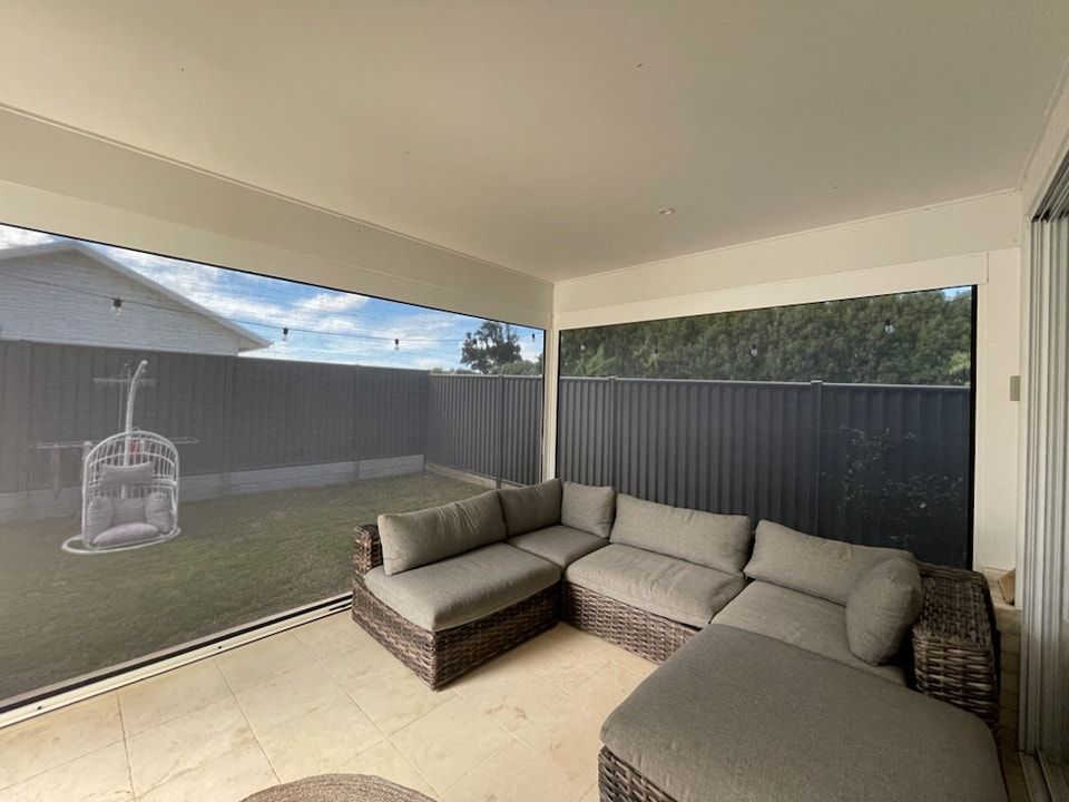 A Living Room With a Couch and Ottoman and a Large Window — Dennys Upholstery & Outdoor Blinds In Evans Head, NSW