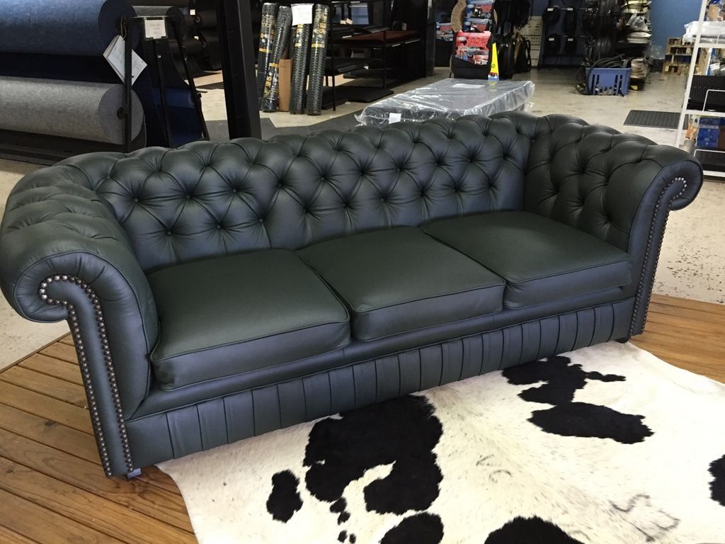 A Black Leather Couch is Sitting on Top of a Cow Print Rug — Dennys Upholstery & Outdoor Blinds In South Lismore, NSW