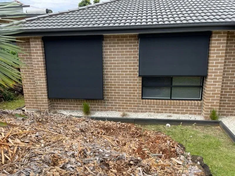 A Brick House With Black Blinds on the Windows — Dennys Upholstery & Outdoor Blinds In South Lismore, NSW