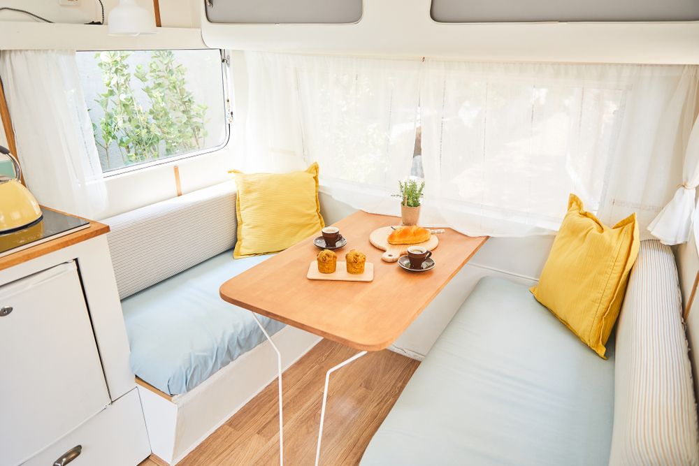 A Camper With a Table and a Couch in It — Dennys Upholstery & Outdoor Blinds In South Lismore, NSW