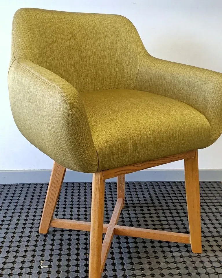 A Yellow Chair With Wooden Legs is Sitting on a Tiled Floor — Dennys Upholstery & Outdoor Blinds In Evans Head, NSW