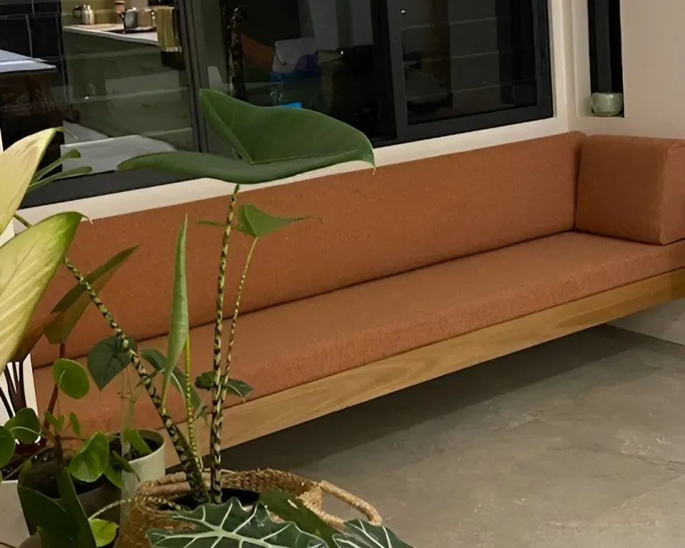 A Living Room With a Couch, Potted Plants and a Window — Dennys Upholstery & Outdoor Blinds In South Lismore, NSW